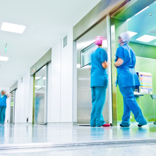 blurred figures wearing medical uniforms in hospital surgery corridor
