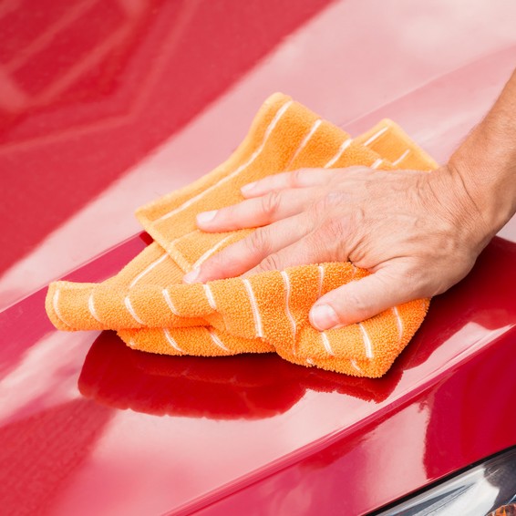 Cropped image of male worker washing red car hood